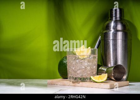 Cocktail d'alcool de punch Ti froid glacé, petit punch, boisson mélangée à base de rhum avec garniture de tranche de citron vert frais, sur fond vert coloré Banque D'Images