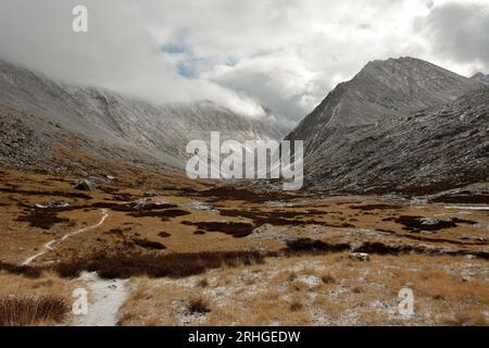 Un sentier étroit traverse une vallée pittoresque, parsemée de la première neige, prise en sandwich entre deux chaînes de montagnes par une journée nuageuse d'automne. Vallée du Th Banque D'Images