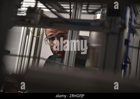 Leuna, Allemagne. 13 juillet 2023. Konrad Gebauer, responsable du développement des procédés de la nouvelle bioraffinerie de Leuna, regarde la caméra à travers une unité de test. Au lieu du pétrole, la société finlandaise UPM souhaite produire des matériaux chimiques à partir du bois. Une coopération a déjà été établie avec la société de vêtements de plein air Vaude pour une veste polaire durable. (À dpa 'du bois au bois : sur le rêve de vêtements fonctionnels sans pétrole') crédit : Simon Kremer/dpa/Alamy Live News Banque D'Images