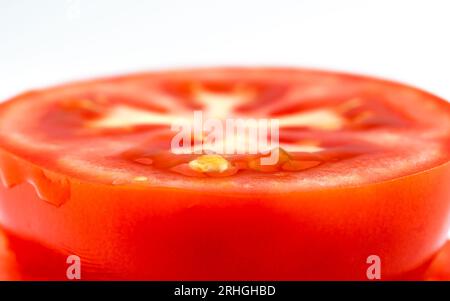 Tomate rouge tranchée sur fond blanc. Morceau rond de tomate fraîche. Arrière-plan de macro Banque D'Images