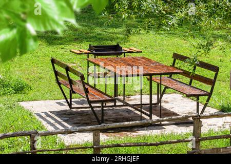 Table de pique-nique vide en bois sur une prairie verdoyante dans un parc public. Table de pique-nique dans une prairie. Banque D'Images