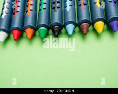 Crayons multicolores pour dessiner sur fond vert. Crayons gros plan. Banque D'Images