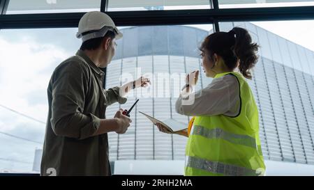 Ingénieurs civils et architectes inspectant et travaillant le chantier de construction et tenant le talkie-walkie Banque D'Images