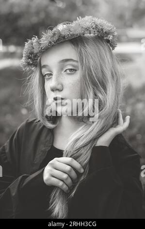 Portrait rapproché d'une belle femme blonde avec une tresse. une fille de 13-15 ans regarde mystérieusement et pensivement dans la caméra. Noir et Banque D'Images