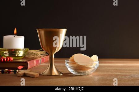 Tasse de vin et hôtes sur table en bois avec bible et bougie pour l'eucharistie noir isolé fond. Vue avant. Banque D'Images