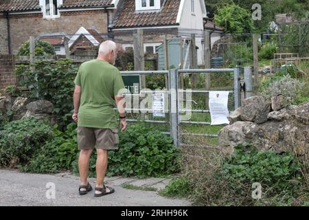 Clevedon, Royaume-Uni. 17 août 2023. Le conseil municipal de Clevedon n'a pas été en mesure d'obtenir une assurance, il a donc été obligé de fermer des installations publiques telles que le bureau du conseil, les courts de tennis et les allotments. Les installations continuent d'être indisponibles aujourd'hui dans cette ville balnéaire populaire. Sur la photo, un homme regarde les portes fermées de l'allotissement. Crédit : JMF News/Alamy Live News Banque D'Images