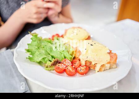 Brioche, oeuf poché, crème d'avocat avec saumon et oeuf. Petit déjeuner sain, protéines. Plat de restaurant. Banque D'Images