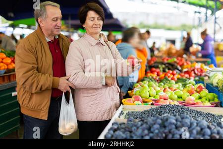 Un homme âgé et une femme choisissent des pommes tout en achetant des fruits Banque D'Images