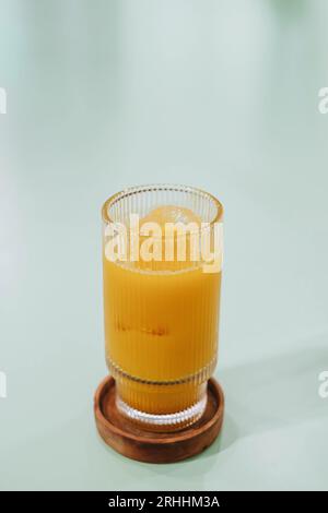 Portrait ou photo de mise au point verticale et sélective d'un verre de glace Kunir ASEM qui est une boisson de médecine traditionnelle javanaise à base de plantes sur fond isolé Banque D'Images