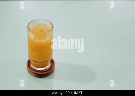 Photo de mise au point sélective d'un verre de glace Kunir ASEM qui est une boisson médicinale traditionnelle javanaise sur une table pastel vert sauge isolée Banque D'Images