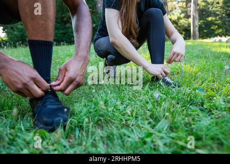 Gros plan des mains de deux sportifs attachant leurs chaussures, photo avec espace copie Banque D'Images