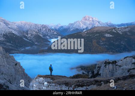 Un touriste se dresse au-dessus du brouillard au bord d'une falaise dans les Dolomites.Emplacement Auronzo rifugio dans le parc national de Tre Cime di Lavaredo, Dolomites, Trentin-Haut-Adige, Italie Banque D'Images