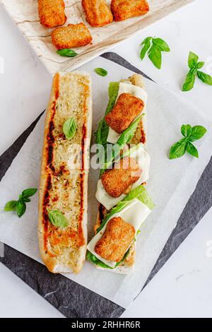 Sandwich panini au poulet grillé avec nuggets de poulet garni de feuilles de basilic frais directement au-dessus du Panini au poulet photo Banque D'Images