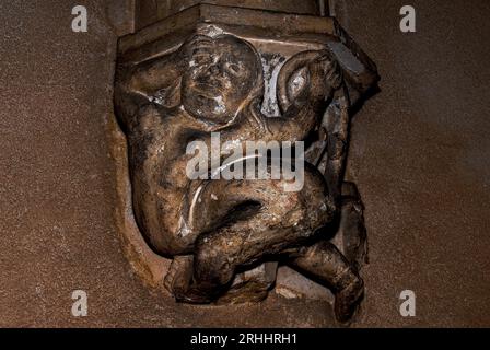 Corps tordu d'un contorsionniste, frottant ses yeux. Sculpté sur le cloître du début des années 1500 Monastère royal de Brou à Bourg-en-Bresse, Auvergne-Rhône-Alpes, France. Banque D'Images