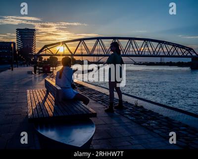 Nijmegen, pays-Bas. 14 août 2023. Deux femmes sont vues profiter du coucher de soleil près de la rivière Waal. Après plusieurs semaines changeantes, les pays-Bas peuvent s’attendre à ce que la météo estivale commence cette semaine. Les températures ont augmenté avec beaucoup de place pour le soleil. Dans les jours suivants, il restera principalement sec et le soleil brillera abondamment de sorte que des températures comprises entre 22 et 28 degrés peuvent être attendues. (Photo Ana Fernandez/SOPA Images/Sipa USA) crédit : SIPA USA/Alamy Live News Banque D'Images