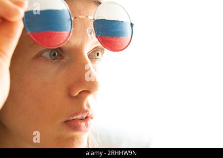 Drapeau de la Russie sur les lunettes d'une fille, aveugle et trompée par la propagande russe, ne voit rien à cause de la propagande Banque D'Images