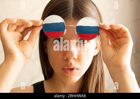 Drapeau de la Russie sur les lunettes d'une fille, aveugle et trompée par la propagande russe, ne voit rien à cause de la propagande Banque D'Images