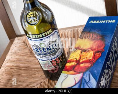 Bouteille d'absinthe et boîte à bouteilles illustrée «Van Gogh» sur siège de chaise en paille rustique. France Banque D'Images