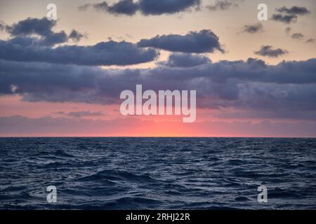 Coucher de soleil rose avec ciel bleu dans l'océan bleu profond. Banque D'Images