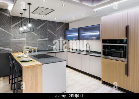 Design intérieur de la cuisine moderne comptoir lavabo armoires blanches construit dans poêle placard en bois avec réfrigérateur four tandis que salle à manger chaises table pla Banque D'Images
