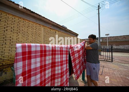 (230817) -- TIANJIN, 17 août 2023 (Xinhua) -- Un villageois diffuse la literie après être rentré chez lui dans le village de Shaoqidi, dans le canton de Huanghuadian, district de Wuqing, dans le nord de la Chine Tianjin, le 17 août 2023. Au total, 15 011 personnes, le dernier groupe de personnes qui avaient été précédemment relocalisées de zones sujettes aux inondations par la rivière Yongding, sont rentrées jeudi dans leurs foyers dans 14 villages de Wuqing. À l'heure actuelle, l'approvisionnement en électricité, en eau et en gaz a été rétabli dans les villages, et l'évaluation et la reconstruction des installations endommagées sont en cours dans les zones locales. (Xinhua/Sun Fanyue) Banque D'Images