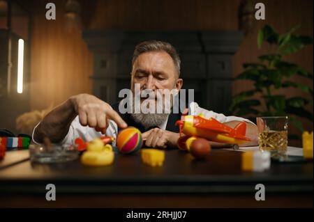 Portrait d'homme d'affaires senior réfléchi jouant des jouets pendant le repos Banque D'Images