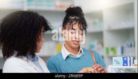 Femme de pharmacie consultante heureuse aidant le client avec sa prescription. Pharmacienne donnant des instructions plus détaillées à son client Banque D'Images