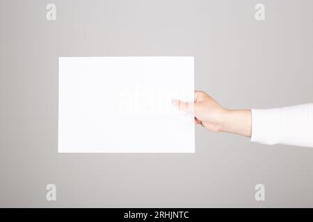 une main féminine tient une feuille de papier vierge. Espace pour le texte Banque D'Images
