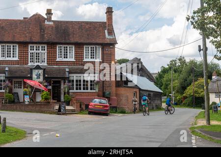 Le Trusty servant Inn dans le centre du village de Minstead, un village New Forest dans le Hampshire, Angleterre, Royaume-Uni, avec des gens à vélo Banque D'Images