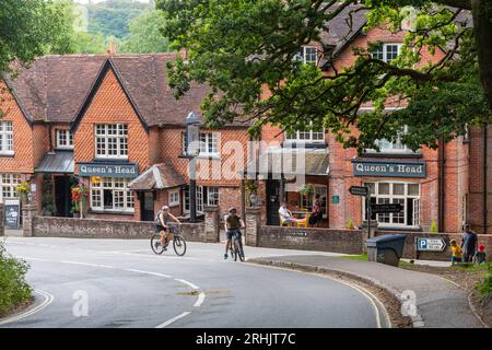 Le pub Queen's Head à Burley, un village de New Forest, Hampshire, Angleterre, Royaume-Uni, avec des gens buvant dehors, marchant et faisant du vélo Banque D'Images