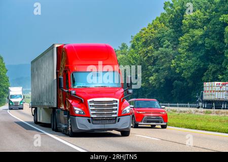 Plan horizontal d'un dix-huit roues rouge conduisant la circulation sur une autoroute inter-États. Banque D'Images