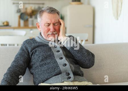 Maux de tête. Malheureux homme âgé d'âge moyen souffrant de maux de tête malade frottant les tempes à la maison. Vieux grand-père aîné mature touchant les temples éprouvant du stress. Homme sentant mal à la tête Banque D'Images