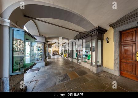 Cuneo, Piémont, Italie - 16 août 2023 : vue des arcades typiques sous des bâtiments historiques avec des magasins de style rétro dans le centre de la via Roma Banque D'Images