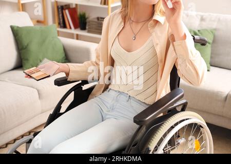 Jeune femme en fauteuil roulant se maquillant à la maison, closeup Banque D'Images