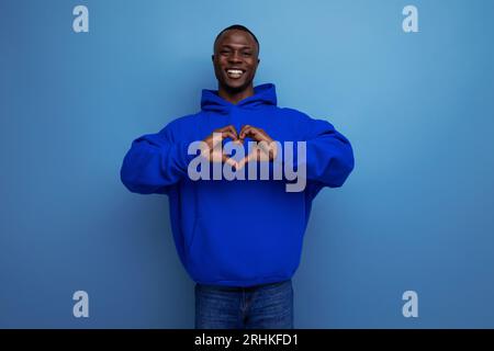 Gros plan d'un Africain à la peau sombre de 25 ans dans un sweat-shirt avec une capuche et un modèle dans un arrière-plan studio avec espace de copie Banque D'Images