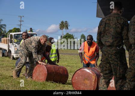 Île de Bougainville, Papouasie-Nouvelle-Guinée. 12 août 2023. Des villageois et des Marines américains roulent des barils de carburant à un avion MV-22B Osprey pour distribution dans des zones reculées à la suite des éruptions du volcan du mont Bagana, le 12 août 2023 sur l’île de Bougainville, Papouasie-Nouvelle-Guinée. Crédit : Caporal Abigail Godinez/U.S. Marines/Alamy Live News Banque D'Images