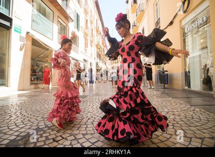 Deux femmes portant des robes de flamenco dansent dans la rue alors qu'elles participent à la foire de Malaga en 2023. Des milliers de personnes se sont rassemblées dans les rues principales de la ville pour participer à la Foire de Malaga dans une ambiance festive. Au cours d'une semaine, des milliers de touristes et de locaux apprécieront les concerts, la danse flamenco dans les rues et d'autres activités telles que la foire de tauromachie et les spectacles équestres. Banque D'Images