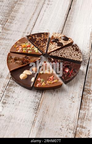 Composition créative chocolat sous forme de pizza aux fruits confits, noix, baies sèches, pizza au chocolat et ingrédients sur fond de bois. Banque D'Images