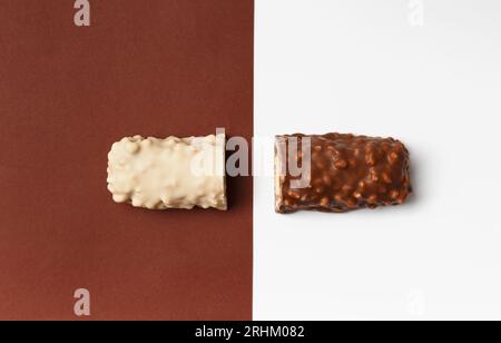 Chocolat blanc et noir sur fond brun et blanc, vue de dessus. Représentation conceptuelle de deux opposés dans le thème du chocolat. Deux moitiés Banque D'Images