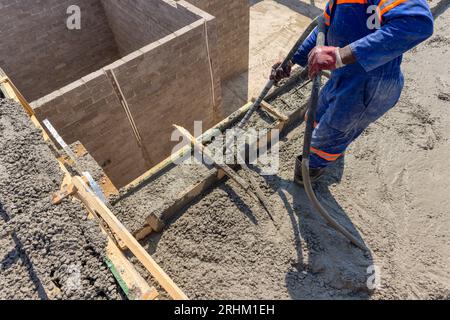 pompe à béton boom, coulant du béton sur le dernier étage ouvrier africain actionnant le tuyau en caoutchouc vibrant Banque D'Images