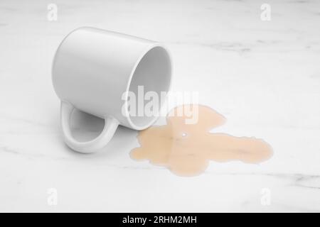 Flaque de liquide et tasse renversée sur la table en marbre blanc Banque D'Images