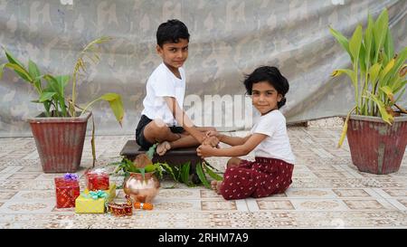 Plan d'une fille indienne attachant rakhi à la main de son frère pendant le festival raksha bandhan à la maison. Banque D'Images