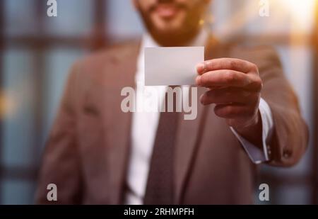 Beau jeune homme donnant carte in modern office Banque D'Images