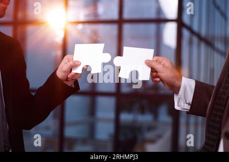 Gros plan des partenaires commerciaux combinant deux pièces de puzzle blanc Banque D'Images