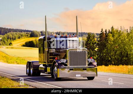 Beau camion américain classique le long de l'autoroute sous le ciel d'heure d'or. Finlande. 2023. Banque D'Images