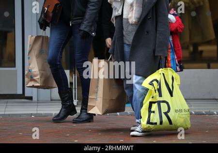 Photo de dossier datée du 26/12/20 de personnes portant des sacs à provisions, alors que les ventes dans le secteur de la vente au détail au Royaume-Uni ont chuté plus rapidement que prévu le mois dernier, en partie grâce au mauvais temps qui a frappé le pays, a déclaré l'Office for National Statistics. Banque D'Images