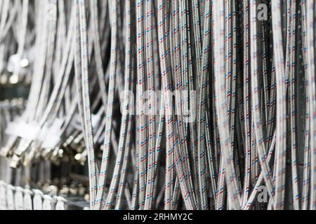 Tuyau flexible en acier inoxydable tressé fermé disposé en rangée contre un mur blanc. Banque D'Images