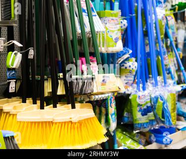 Brosses en plastique pour le nettoyage des locaux. Assortiment de balais multicolores dans le magasin. Gros plan Banque D'Images