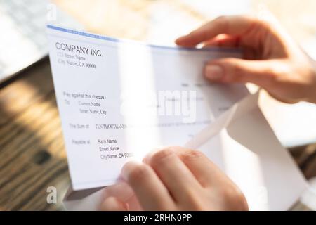 Close-up de l'homme d'affaires d'ouverture de l'enveloppe avec un chèque en bois de plus de 24 Banque D'Images