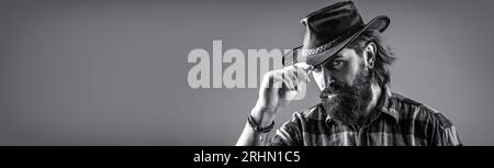 Chapeau de cow-boy. Portrait d'un jeune homme portant un chapeau de cow-boy. Cowboys en chapeau. Beau macho barbu. Noir et blanc Banque D'Images